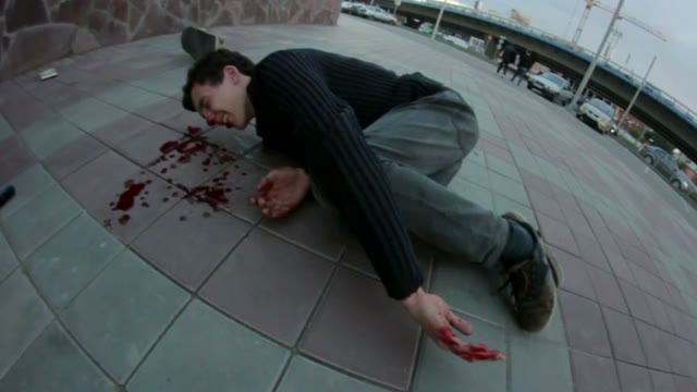 Young Man Lying On The Sidewalk. He's Bleeding From The Nose
