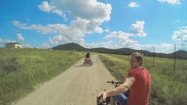A Young Man Riding A Quad Bike On A Field And Shoots On Selfie Sticks Himself