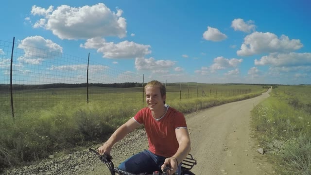 A Young Man Riding A Quad Bike On A Field And Shoots Himself With Selfie Sticks