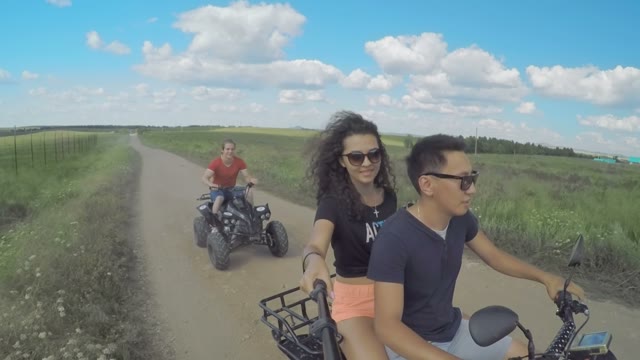 A Young Man Riding A Quad Bike On A Field And Shoots On Selfie Sticks Himself