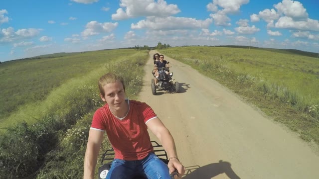 A Young Man Riding A Quad Bike On A Field And Shoots On Selfie Sticks Himself