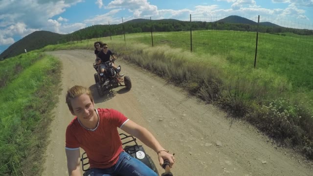 A Young Man Riding A Quad Bike On A Field And Shoots On Selfie Sticks Himself