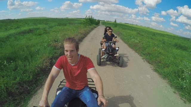 A Young Man Riding A Quad Bike On A Field And Shoots On Selfie Sticks Himself