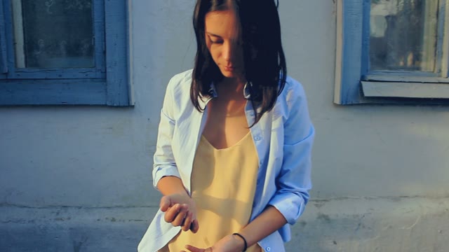 Girl In A Yellow T-shirt Playing With Stones On A Background Of Blue Wall
