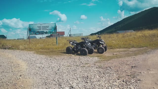 Young People Sits On ATVs To Travel On Summer Field