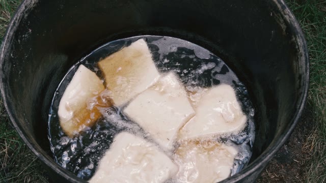 Pieces Of Dough Fried In Hot Oil In A Large Bucket