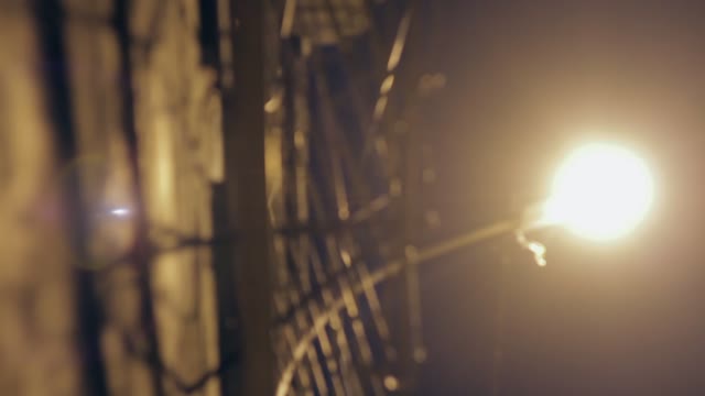 Large Fence With Barbed Wire At Night Lit By A Lantern
