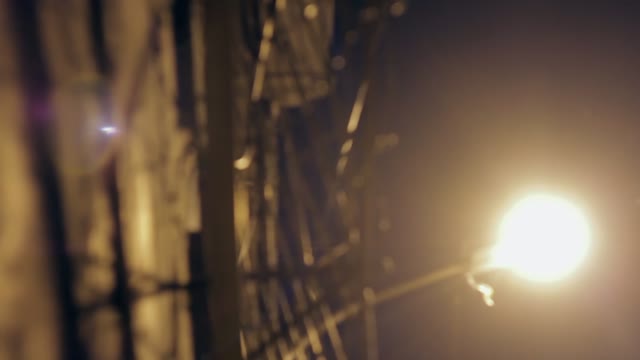 Large Fence With Barbed Wire At Night Lit By A Lantern