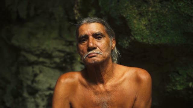 Adult Male In Shorts Sitting On A Rock In A Cave