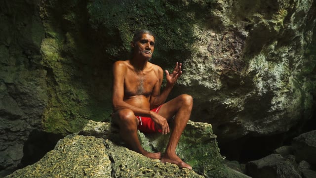 Adult Male In Shorts Sitting On A Rock In A Deep Cave