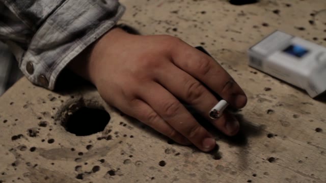 Man Smokes In A Dark Room. Close-up Of Hands