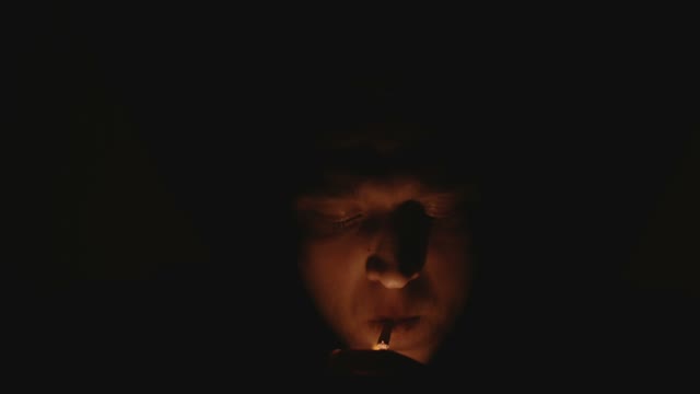 Man Ignites And Smokes A Cigarette In Darkness Close-up