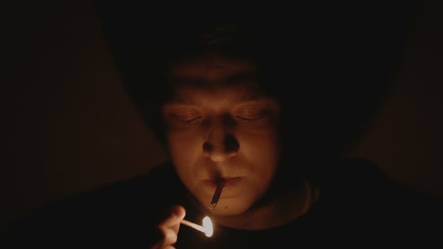 Man Ignites And Smokes A Cigarette In Darkness Close-up