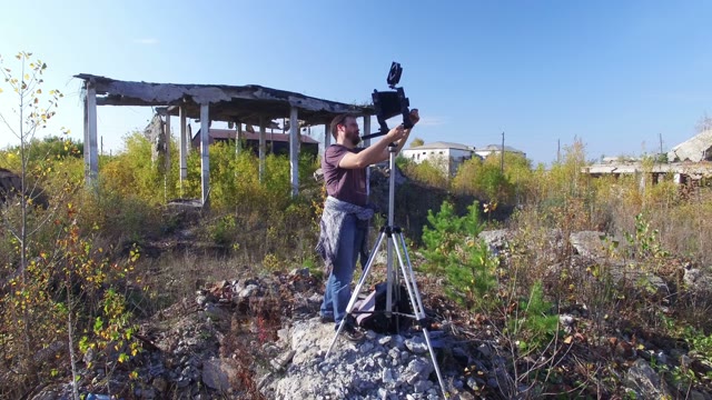 Man Stands With Video Equipment Among Destroyed Buildings
