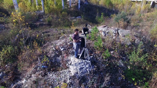 Man Stands With Video Equipment Among Destroyed Buildings