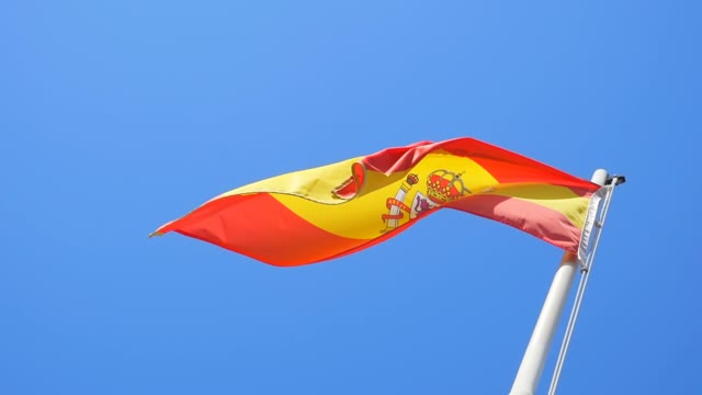 Spanish Flag Flying In The Blue Sky Background