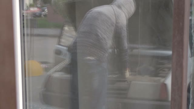 Reflection In The Glass Of A Man Repairing Car