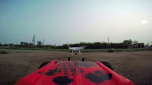 RC Cars With A Camera Rides On The Field And Filmed The Quadrocopter, Flying In