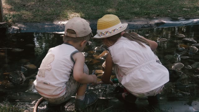 Children Sit Near The Stream And Playing