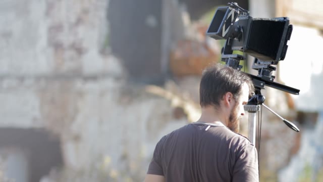 Man Adjusts The Retro Camera Among The Ruins