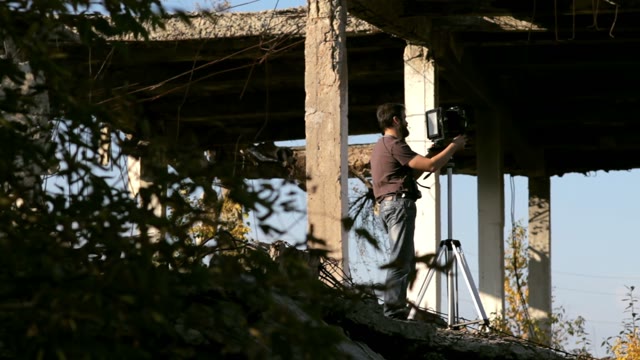 Man Adjusts The Retro Camera In Ruins
