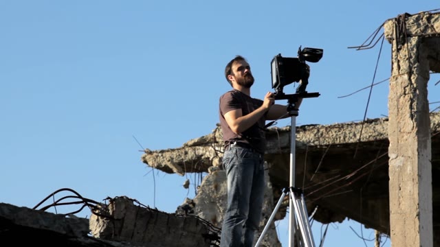 Man Adjusts The Retro Camera In Ruins