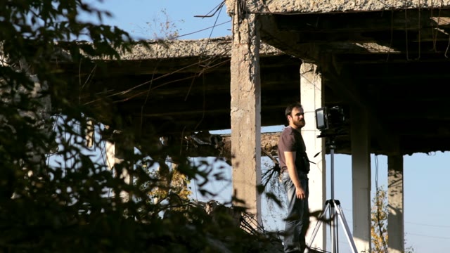 Man Adjusts The Retro Camera In Ruins