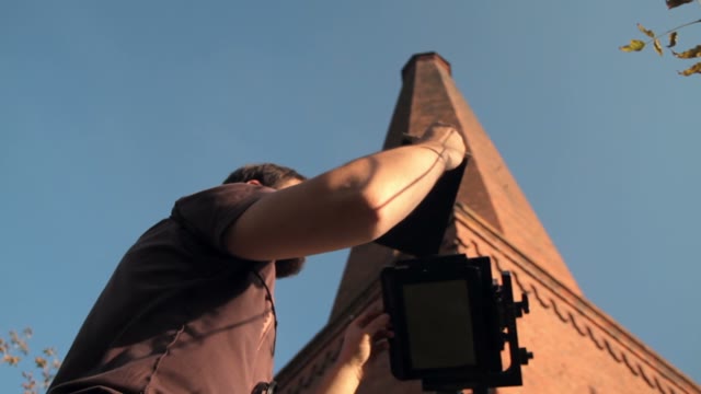 Man Sets Retro Camera Next To The Chimney