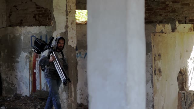 Man Walks With Retro Camera Among The Ruins