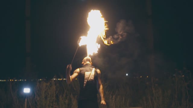 Daring Muscular Guy Breathes Fire At Night
