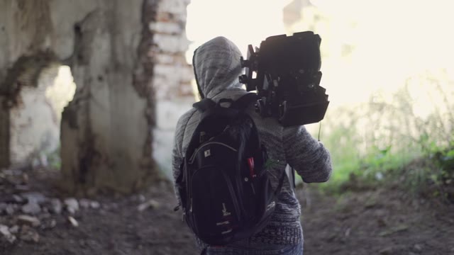 Man Walks With An Retro Camera Among The Ruins