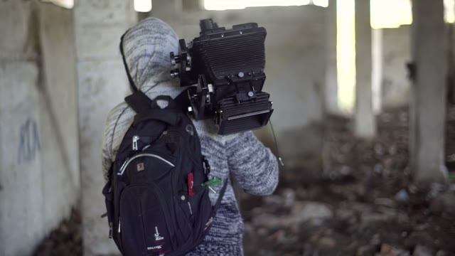 Man Walks With An Retro Camera Among The Ruins