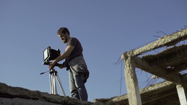 Man Puts A Retro Camera Near A Ruined Building