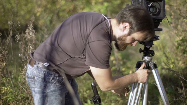 Man Puts A Retro Camera Among Green Trees