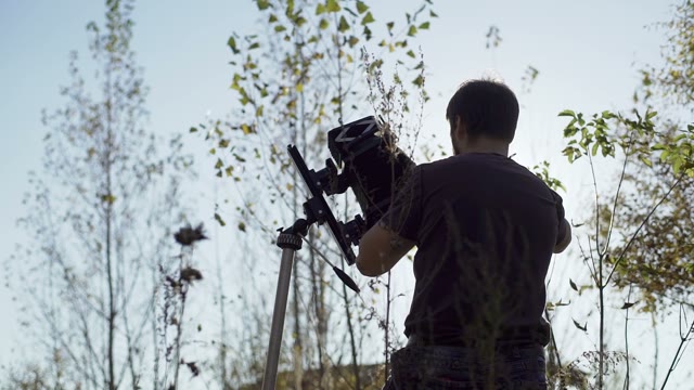 Man Puts A Retro Camera Among Green Trees
