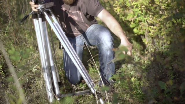 Man Puts Retro Camera Among Green Trees Close-up