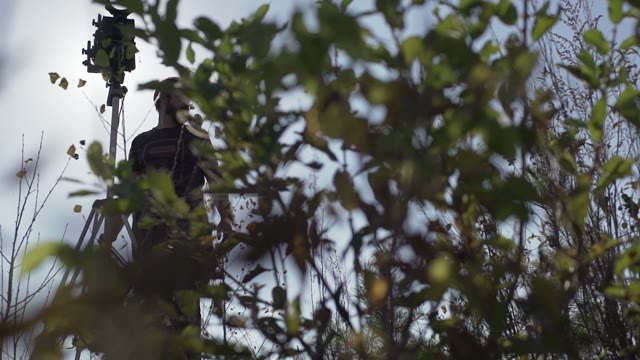 Man With Retro Camera Among Green Bushes