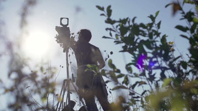Man Sets Retro Camera Among Green Bushes