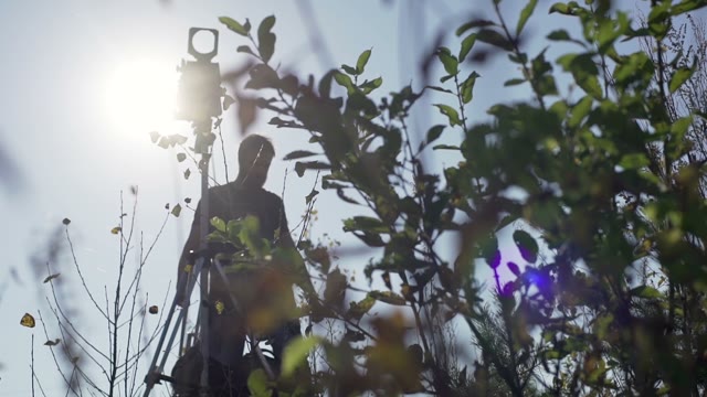 Man Sets Retro Camera Among Green Bushes