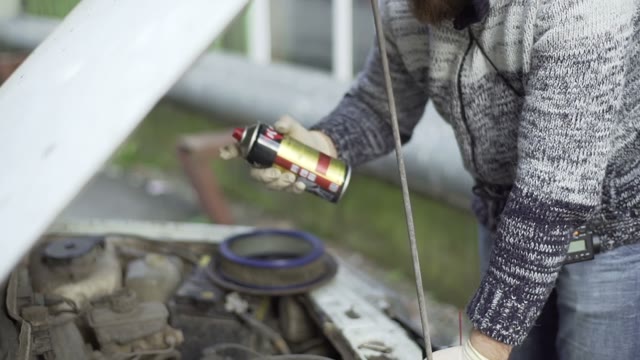 Man Sprinkles Car Engine Close-up