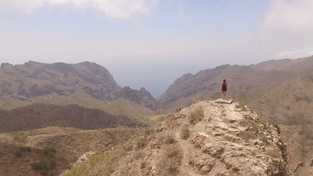Female Looking At The Valley From The Top Of A Huge Mountain, Aerial