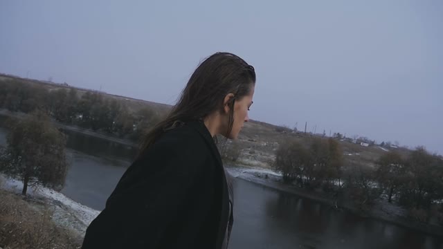 The Girl Looks At The Bridge On The River During Snowfall