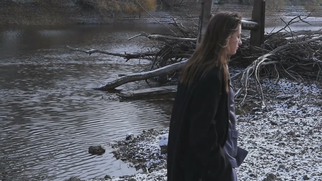 Woman Runs Along The Frozen River Where It Is Snowing