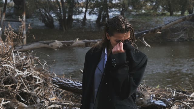 Tanned Girl In A Black Coat Freezing Near The River