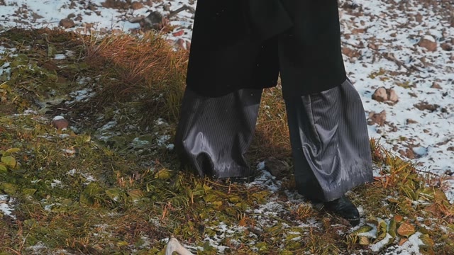 Women's Legs In Slacks Are Going On Frozen Autumn Leaves In The Snow