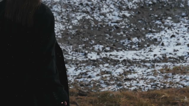 The Girl In The A Black Coat Walking On Snow-covered Field