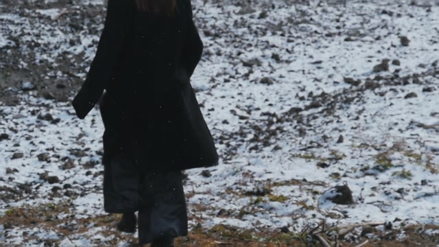 The Girl In The A Black Coat Walking On Snowy Hills