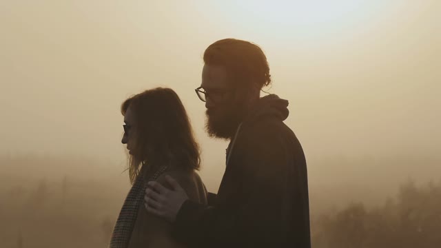 The Guy Holds His Girlfriend's Shoulders In The Sun-drenched Evening Light