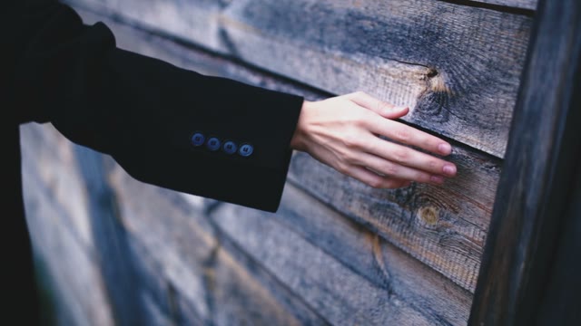 The Thin Female Hand On A Background Of A Wooden House