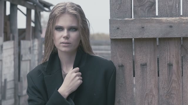 Pretty Blond Girl In A Black Near The Fence On A Cloudy Day